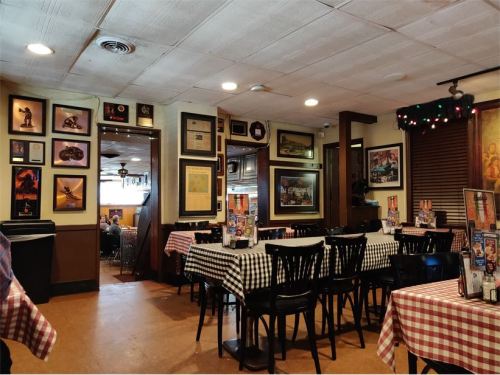 Cozy restaurant interior with checkered tablecloths, framed photos on the walls, and a warm, inviting atmosphere.
