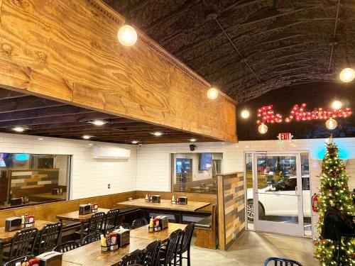 Interior of a restaurant featuring wooden accents, tables, and a Christmas tree, with a sign reading "The Avenue."