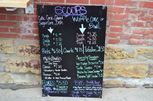 Menu board displaying ice cream prices for scoops, cones, bowls, sundaes, and floats. Prices range from $4 to $8.25.