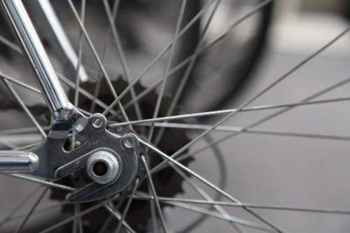 Close-up of a bicycle wheel hub and spokes, showcasing metallic details and a blurred background.