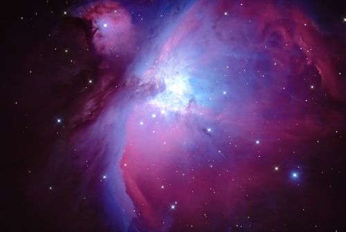 A vibrant cosmic scene featuring swirling clouds of pink and blue gas, with bright stars scattered throughout the dark space.
