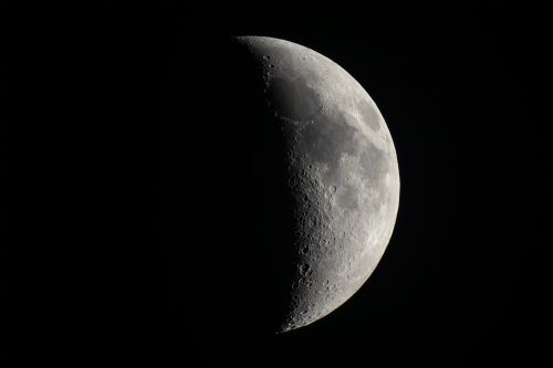 A close-up view of a crescent moon against a dark sky, showcasing its craters and surface details.