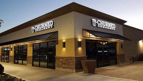 Exterior of Churned Creamery, featuring a modern design with illuminated signage and a welcoming entrance.