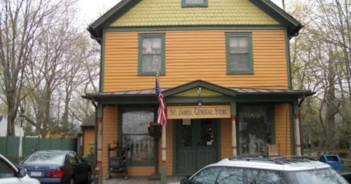 A yellow and green two-story building with a sign reading "St. James General Store" and parked cars in front.