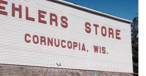 Sign on a building reading "Ehlers Store, Cornucopia, Wis." against a clear blue sky.