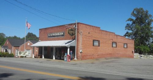 A brick building with a sign reading "E.N. Washburn," featuring a porch and an American flag in front.