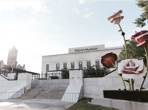 Frit Art Museum with large flower sculptures in the foreground and a clock tower in the background.