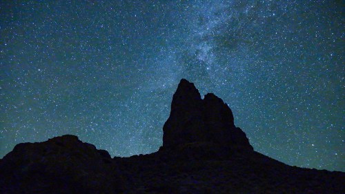 Silhouette of rugged rock formations against a starry night sky with the Milky Way visible.