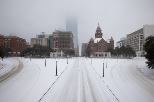 A snowy cityscape with a foggy skyline, featuring historic buildings and empty streets.