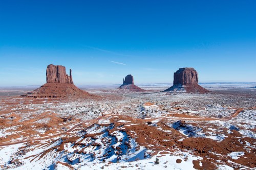 Snow-covered landscape featuring three iconic rock formations under a clear blue sky.