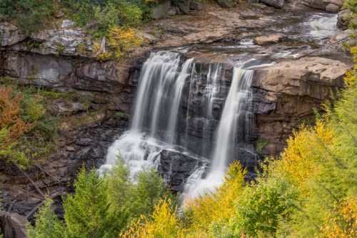 A serene waterfall cascading over rocky cliffs, surrounded by vibrant autumn foliage.