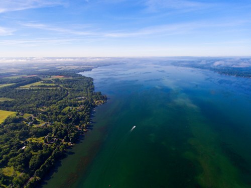 Aerial view of a serene lake surrounded by lush greenery and a small boat gliding across the water.