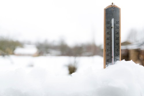 A thermometer stands in snow, showing a temperature reading in a winter landscape.