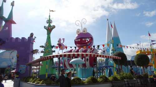 Colorful amusement park scene featuring whimsical structures, a large purple creature, and festive decorations.