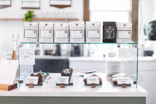 Display case with baked goods and coffee bags, including muffins and croissants, in a bright café setting.