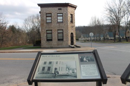 Historic stone building labeled as the Bank of Glen Jean, with an informational sign in the foreground.