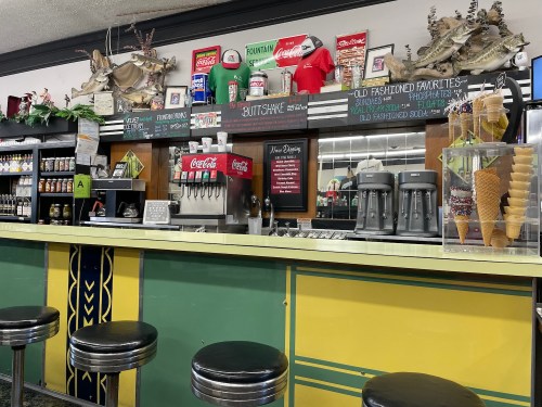 A vintage diner counter with soda fountains, ice cream cones, and retro decor, featuring fishing-themed decorations.