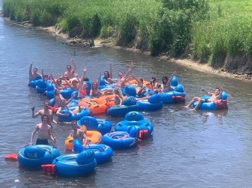 A group of people enjoying a sunny day floating on colorful inner tubes in a river.