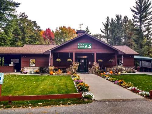A rustic wooden lodge with a sign reading "Paw's Farm," surrounded by colorful flowers and autumn foliage.
