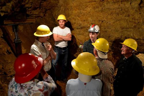 A group of people in hard hats discussing in a dimly lit underground mine.