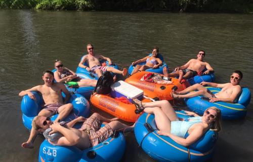 A group of people relaxing on colorful inner tubes in a river on a sunny day.
