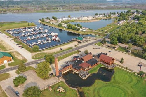 Aerial view of a marina with boats, a restaurant, and green landscapes along a river.