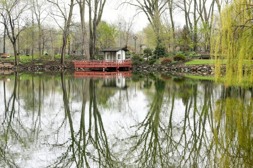 A serene lake scene with a small red dock, surrounded by trees and reflections in the calm water.