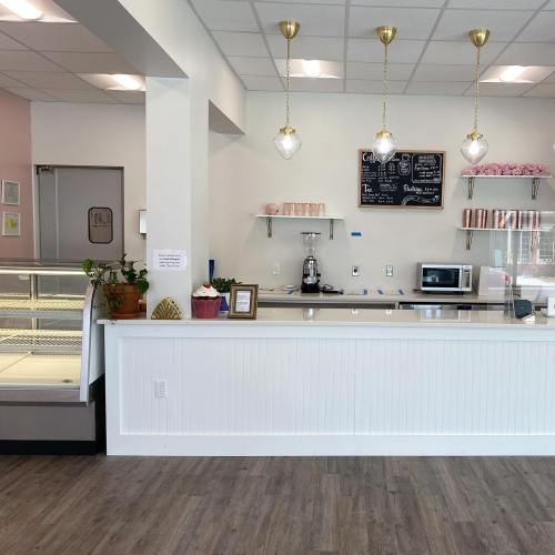 A bright café interior featuring a counter with a coffee machine, microwave, and a chalkboard menu.