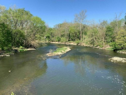 A serene river winding through lush greenery under a clear blue sky.