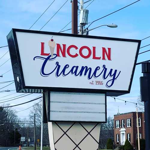 Sign for Lincoln Creamery, established in 1986, with a blue and red design against a clear sky.