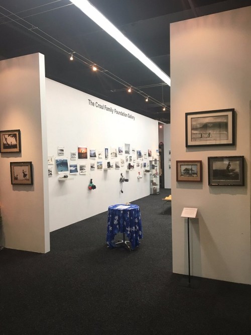 Interior view of the Croul Family Foundation Gallery, featuring framed artworks and a blue tablecloth display.