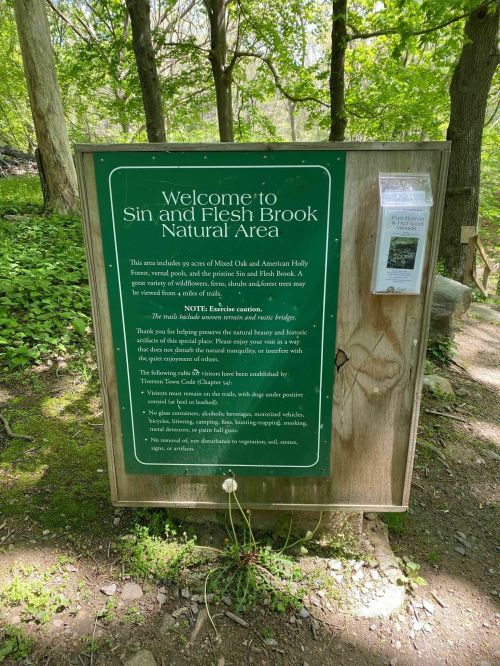 Sign welcoming visitors to Sin and Flesh Brook Natural Area, detailing trails and natural features in a wooded setting.