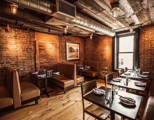 Cozy restaurant interior with brick walls, wooden floors, and stylish seating arrangements. Warm lighting enhances the ambiance.