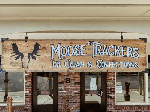 Sign for "Moose Trackers Ice Cream & Confections" featuring moose antlers design, located above a storefront entrance.