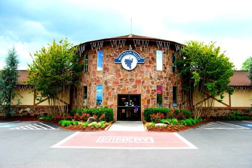 A stone building with a round design, featuring a sign for a winery and surrounded by greenery and flowers.