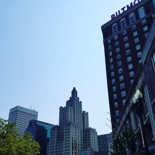 City skyline featuring tall buildings under a clear blue sky, with a focus on the Butmore Hotel sign.