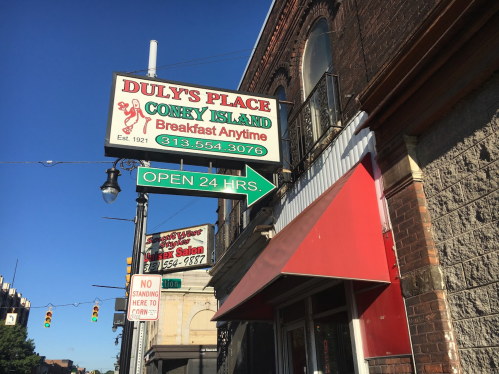 Sign for Duly's Place Coney Island, open 24 hours, with a red awning and nearby businesses visible.