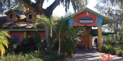 Colorful exterior of Hurricane Dockside Grill, featuring palm trees and a welcoming entrance under a sunny sky.