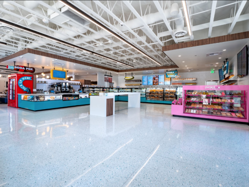 Bright, modern food court with colorful vendor stalls and a display case of pastries. Spacious and well-lit interior.