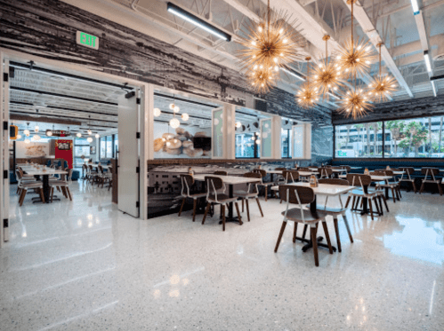 Modern dining area with wooden tables, stylish lighting, and a bright, open atmosphere.
