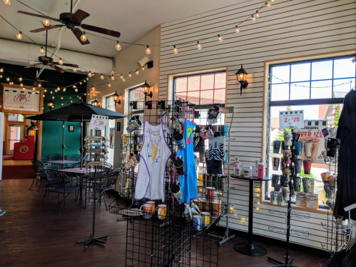 A cozy shop interior with merchandise displays, string lights, and seating areas.