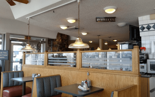 Interior of a diner with wooden partitions, booths, and overhead lights, featuring a cozy, casual atmosphere.