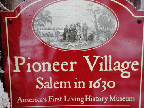 Sign for Pioneer Village, Salem in 1630, featuring historical illustration and text about America's first living history museum.