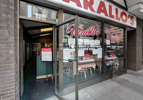 Entrance of Varallo's restaurant, featuring a sign and menu, with tables visible inside.