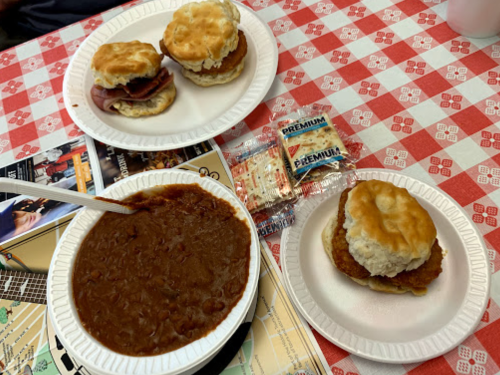 Two plates of food on a checkered tablecloth: biscuits with meat and a bowl of chili, accompanied by crackers.