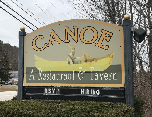Sign for "Canoe: A Restaurant & Tavern" with a canoe graphic, featuring "RSVP" and "HIRING" messages below.