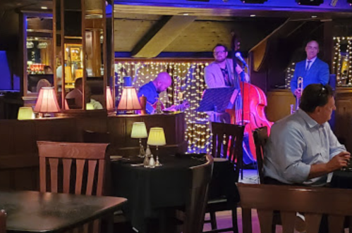 A jazz band performs in a cozy restaurant with dim lighting and tables set for dining.
