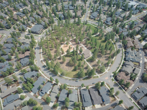 Aerial view of a circular neighborhood with houses surrounding a central park area filled with trees.