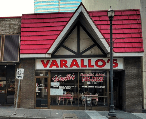 Exterior of Varallo's restaurant with a red roof, large windows, and a sign featuring the name and offerings.