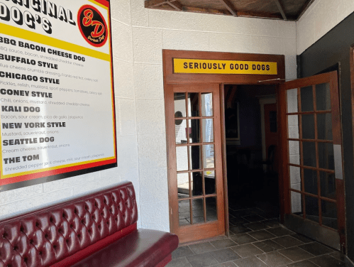 Interior view of a restaurant entrance with a menu on the wall and a sign reading "Seriously Good Dogs."